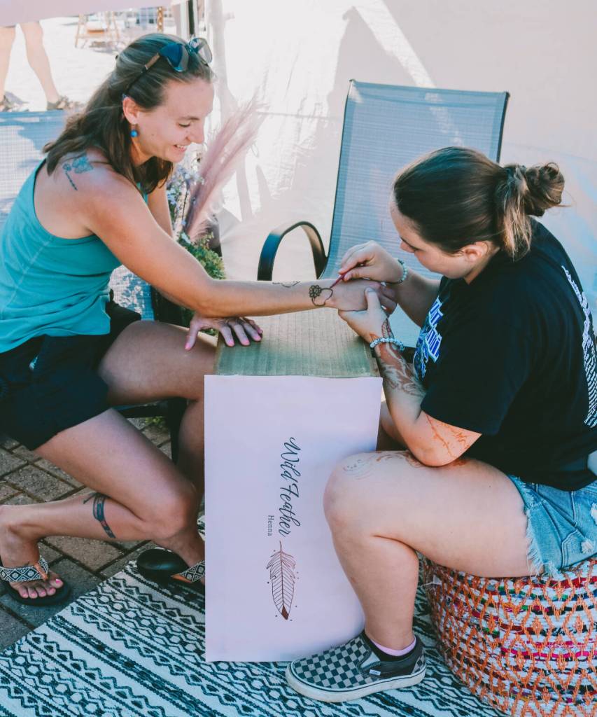 Photo courtesy of Sequim Farmers & Artisans Market/SFAM / Patience Edwards applies a henna tattoo to a customer at the Wild Feather Henna booth. Henna tattoos are temporary and plant-based.