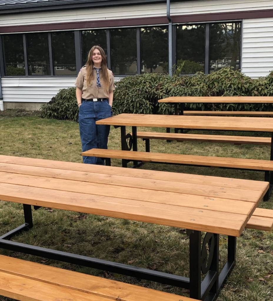 Photo courtesy of Marilyn Mason / Jenna Mason stands by picnic tables she had created for the Sequim YMCA, for her Eagle Scout project.