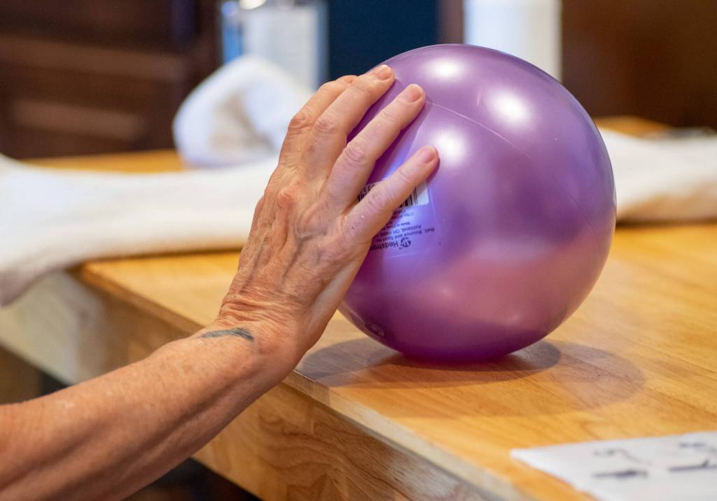 Photo by Emily Matthiessen / Therapy client Sandy Pufky-Negus uses a ball to assist with wrist extension at Peak Performance Therapy Center in Sequim.