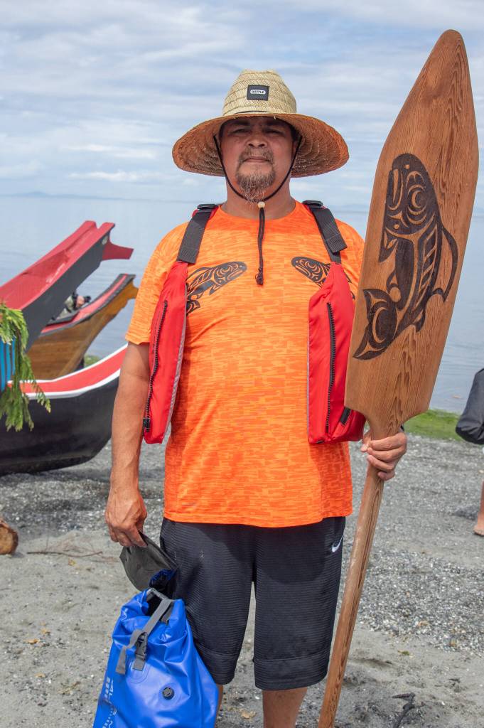 Sequim Gazette photoS by Emily Matthiessen
Above: Carver Michael Hall, culture coordinator for the Puyallup tribe, is also a skipper on his canoe familys canoe, which rests for the night at Jamestown Beach.
At left: Josiah Powless, 7-years-old, holds the bow of a canoe as a member of the canoe family requests permission to land on Jamestown Sklallam shore.
Below: Puyallup canoe family members pose with their canoe on the Jamestown Beach on July 25 after pulling from the lower Elwha.