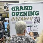 Sequim Gazette photo by Matthew Nash/ Christine Rich of Sequim scans a QR code to try and win a prize at the Aug. 10 grand opening of the Sportsmans Warehouse in Sequim.