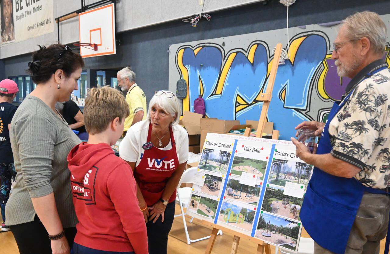Sequim Gazette photo by Michael Dashiell / Stephanie and Jim Sherman with the League of Women Voters talk with Elijah Malkasian, 9, of Sequim, at the Aug. 26 Back to School Fair, about playground options the City of Sequim is considering. Fair attendees were asked to vote on their favorite of three choices; more than two-thirds of the respondents picked Forest Creature, league representatives said.