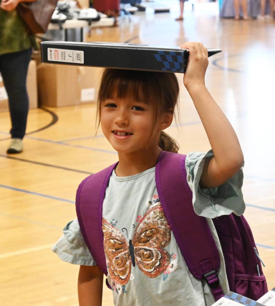Sequim Gazette photo by Michael Dashiell / Fern Ollerman, 6, finds a unique way to carry a 3-ring binder at the Aug. 26 Back to School Fair. Ollerman is entering first grade.