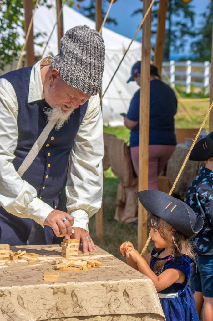 Sequim Gazette file photo by Emily Matthiessen / Bill Huls of the Gilded Thistle, from Renton, plays a stacking game that looks very familiar with three-year-old Aliya Jones at the Northwest Colonial Festival in 2022. It returns Labor Day weekend Sept. 31-Sept. 3 to George Washington Inn.