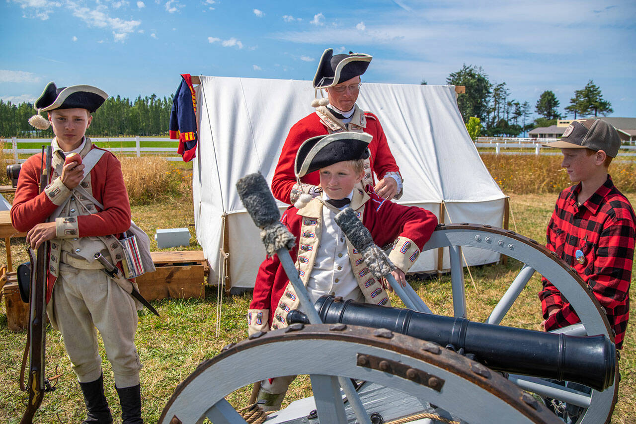 Sequim Gazette file photo by Emily Matthiessen / Dressed as British soldiers at the time of the American Revolution, Peter Berneking of Sequim, Thomas House-Higgins of Olympia and Luke Berneking explain about how a three pound ball fits into this particular cannon while Caleb Berneking looks on at the 2022 Northwest Colonial Festival. It returns Labor Day weekend Sept. 31-Sept. 3 to George Washington Inn.