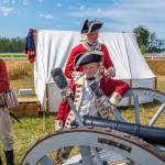 Sequim Gazette file photo by Emily Matthiessen / Dressed as British soldiers at the time of the American Revolution, Peter Berneking of Sequim, Thomas House-Higgins of Olympia and Luke Berneking explain about how a three pound ball fits into this particular cannon while Caleb Berneking looks on at the 2022 Northwest Colonial Festival. It returns Labor Day weekend Sept. 31-Sept. 3 to George Washington Inn.