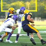 Sequim Gazette photo by Michael Dashiell / Sequim's Charlie Grider (11) and James Mason look to take down Forks running back Brody Lausche in the first half of the Wolves' season-opener at Forks on Sept. 1.
