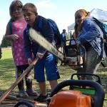 Sequim Gazette file photo by Matthew Nash/ At the 2019 Dungeness River Festival, Eden Holloway and other students hold tools, including a chainsaw, that members of the Backcountry Horseman Peninsula Chapter use to create trails in the area.
