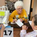 Sequim Gazette photo by Matthew Nash/ Gretha Davis greets third graders Andre Turner and Leilanie Arellano Gallengos at the information Booth inside the Dungeness River Nature Center on Sept. 22. Students could get passports during the festival to visit different booths to receive stamps and a chance to win a prize. Davis asked students how many times theyve visited the center.