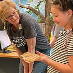 Sequim Gazette photo by Matthew Nash/ During the Dungeness River Festival, Volunteer Stacey Fradkin talks to Jayne Caulfield about the weight of a red-tailed hawks wing.