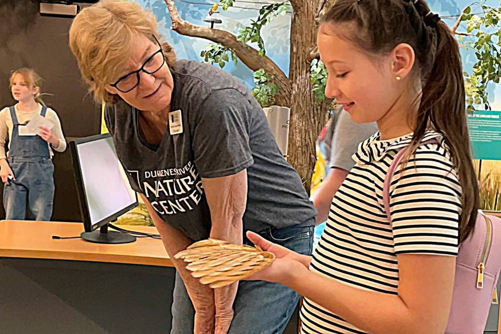 Sequim Gazette photo by Matthew Nash/ During the Dungeness River Festival, Volunteer Stacey Fradkin talks to Jayne Caulfield about the weight of a red-tailed hawks wing.