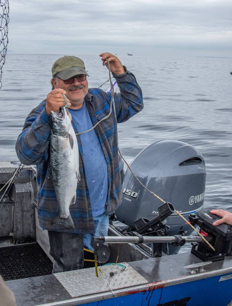 Sequim Gazette photo by Emily Matthiessen / An anonymous fisherman proudly shows his catch to the Washington State Fish and Wildlife police, who check to make sure the catch card matches up with the fish on board and that the fish are the legal size, limit and type.