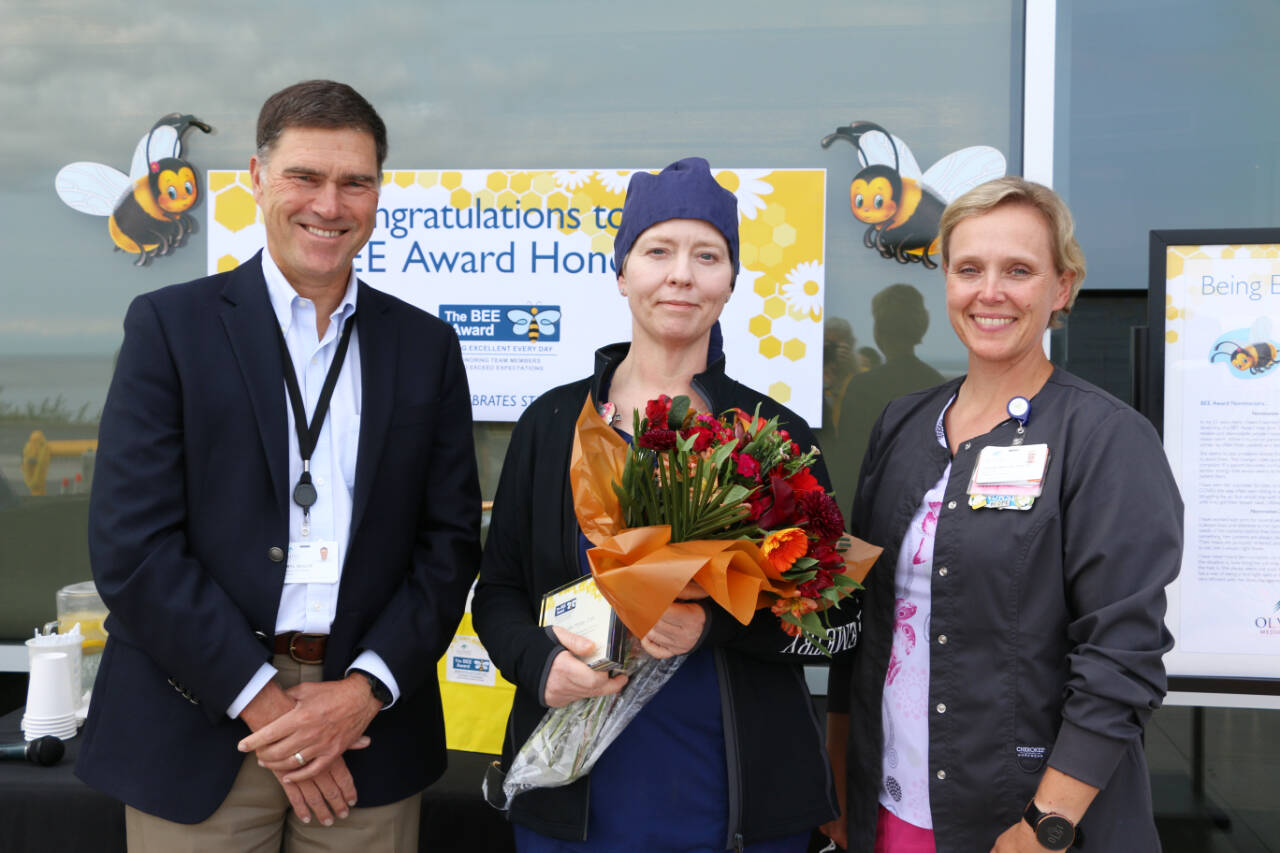 Photo courtesy of Olympic Medical Center
Jennifer McKee, an Olympic Medical Center ICU/telemetry certified nursing assistant (at center), receives a BEE (Being Excellent Every Day) Award from OMC CEO Darryl Wolfe and ICU/telemetry director Katrin Junghanns-Royack.