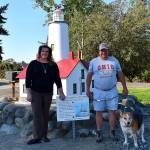Photo courtesy Monica Berkseth/ Beth Pratt, executive director of the Sequim-Dungeness Valley Chamber of Commerce, stands with Chuck French and Bullet the dog by the replica New Dungeness Light Station that he recently repaired and painted after 100-plus hours of volunteer work.