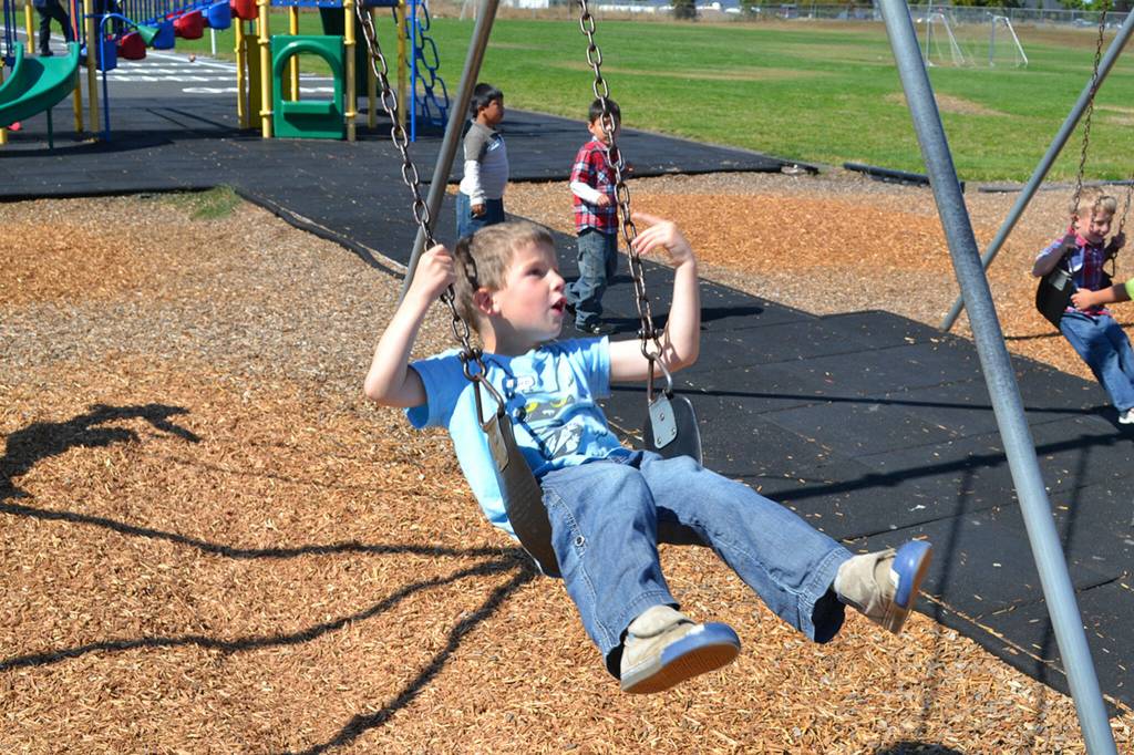 Sequim Gazette file photo by Matthew Nash/ Five-year-old Win Jones swings next to classmates during their first day of kindergarten.