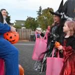 Sequim Gazette file photo by Michael Dashiell / Ava and Ellie Schoessler talk with  and get some candy from  pastor Roger Stites at Faith Lutheran Churchs walk-through trunk-or-treat event last Halloween.