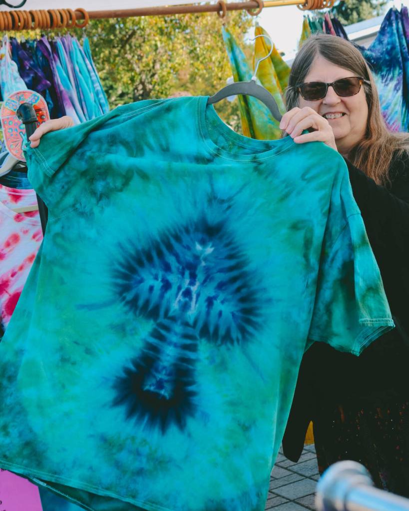 Photo by Bailey Loveless/SFAM / Karen Bell shows off a unique tie-dye creation for a customer. The clothing pieces have been upcycled to breathe new life into discarded materials.