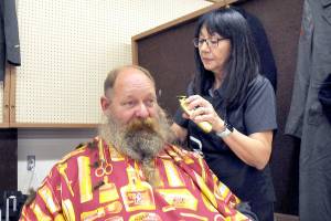 U.S. Navy veteran Brent Brant of Port Hadlock gets a haircut from Susan Gile, owner of Benny's Barbershop in Sequim, during Thursday's Port Angeles Stand Down at the Clallam County Fairgrounds. The event was designed to provide direct services and connect veterans to a variety of assistance organizations, as well as offer clothing, medical services and a meal. (Keith Thorpe/Peninsula Daily News)