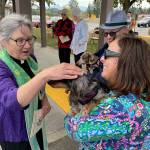 Sequim Gazette photo by Matthew Nash/ Pastor Desi Larson blesses Molly the dog as owner Laura Checkman holds her next to Joel Swenning and Molly the dog. Checkman said theyre new to the church and area as of this summer and it was their first time at a pet blessing.