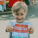 Photo courtesy Sequim Farmers & Artisans Market/ Ollie, a market guest, holds up a Kids Day voucher. Thanks to Nutritious Movements partnership, were able to facilitate hands-on experience with local food for all ages.