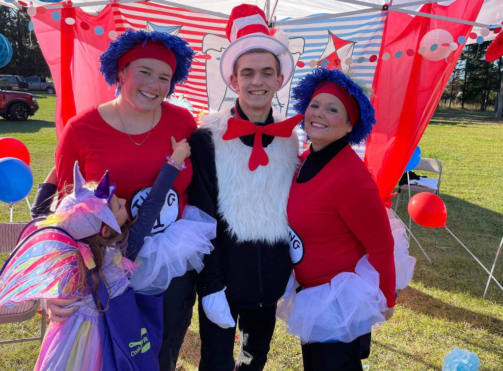 Inspired by Dr. Seuss Cat in the Hat, Sequim Irrigation Festival royalty and royalty mom, from left, Skyler Krzyworz, Fred Cameron, and Lynn Horton, join in on the Sequim Prairie Granges Fall Festival with a hug from a friend.