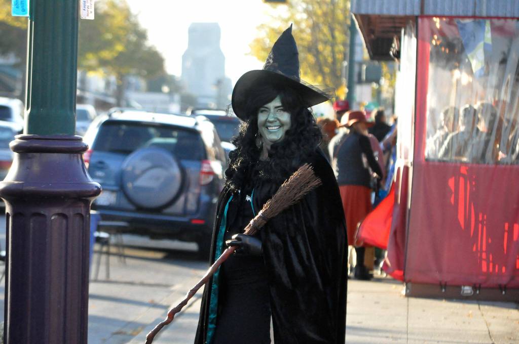 Sequim Gazette photo by Matthew Nash/ Beth Pratt, executive director of the Sequim-Dungeness Valley Chamber of Commerce, helps trick-or-treaters cross Washington Street on Halloween.