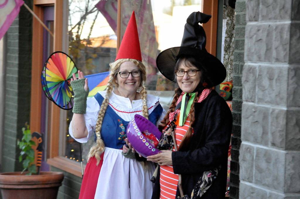 Outside Pondicherri, Kathy Greenwald, operations manager, left, and Kathy Nichols, sales associate, pass out candy on Halloween to passers-by.