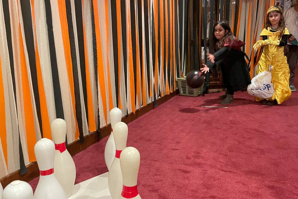 Sequim Gazette photo by Matthew Nash/ Inside the Fifth Avenues bat cave, Allison Washburn, 6, bowls as Harry Potter while Avery Anasasi, 6, as Belle waits her turn on Halloween night.