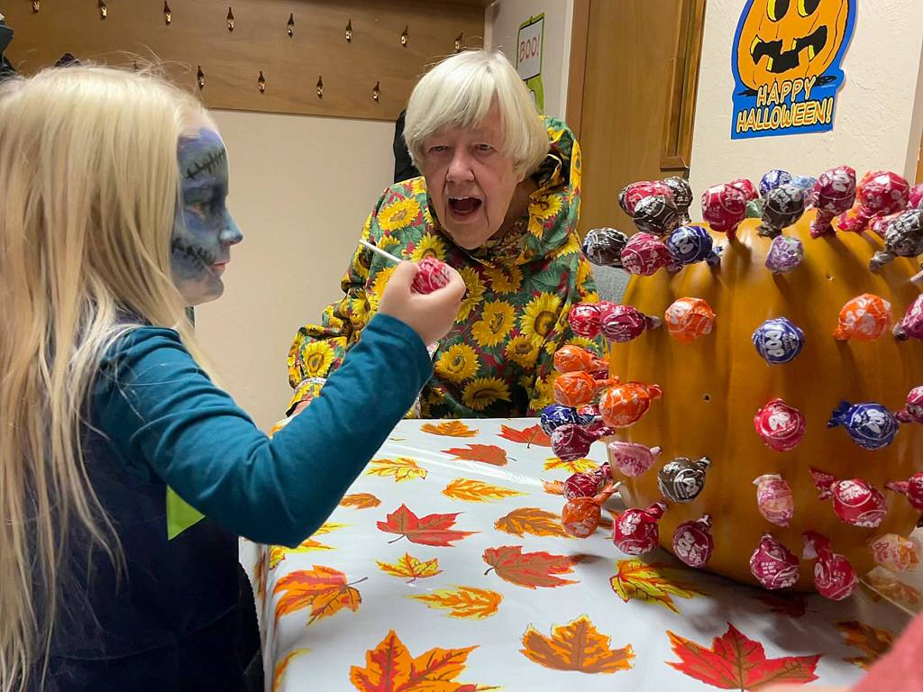 Dressed as a zombie Seahawks cheerleader, 5-year-old Glacier Linch pulls a lollipop for a prize with help from church member Judy Norton at Faith Lutheran Churchs Harvest Festival on Halloween night.
