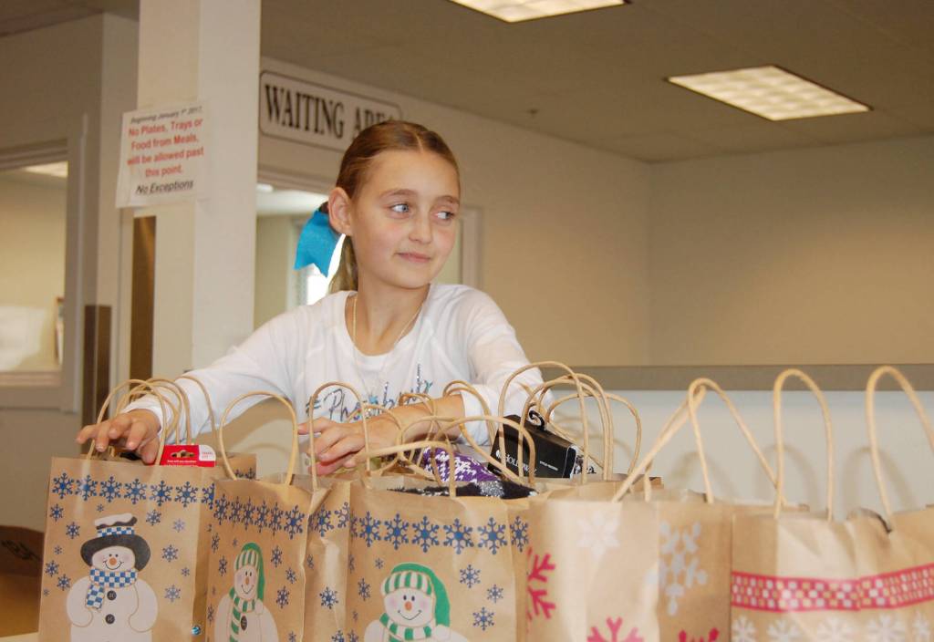 Sequim Gazette file photo by Erin Hawkins/ River Jensen, 10, hands out gift bags full of socks, hats and toiletries at the Salvation Army in Port Angeles in December 2016. She continues the project this year as a senior at Sequim High School.