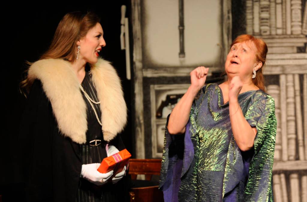 Martha Gillette (portrayed by Cheryl DiPietro), right, reacts to a story from Aggie Wheeler (Merrin Packer) in an early scene of The Games Afoot or Holmes for the Holidays.