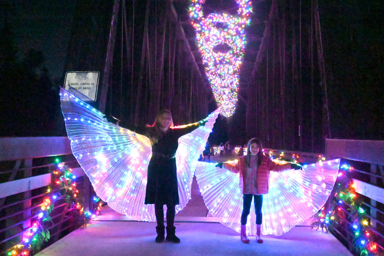 Sequim Gazette photo by Michael Dashiell / Vanessa Fuller, left, and, Raelynn Dickinson, 7, enjoy their illuminated costumes at Sequims Railroad Bridge following the lighting ceremony on Nov. 16.