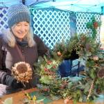 Photo by Keith Thorpe/Olympic Peninsula News Group/ Glynda Ball of Sequim puts the finishing touches on a self-made wreath at a wreath-making station at the Dungeness River Nature Centers Nature Mart on Nov. 18. The event, a fundraiser for the nature centers education programs, also featured a gift mart of hand-crafted, nature-related gifts, a bake sale and photo opportunities with the centers taxidermic animals.
