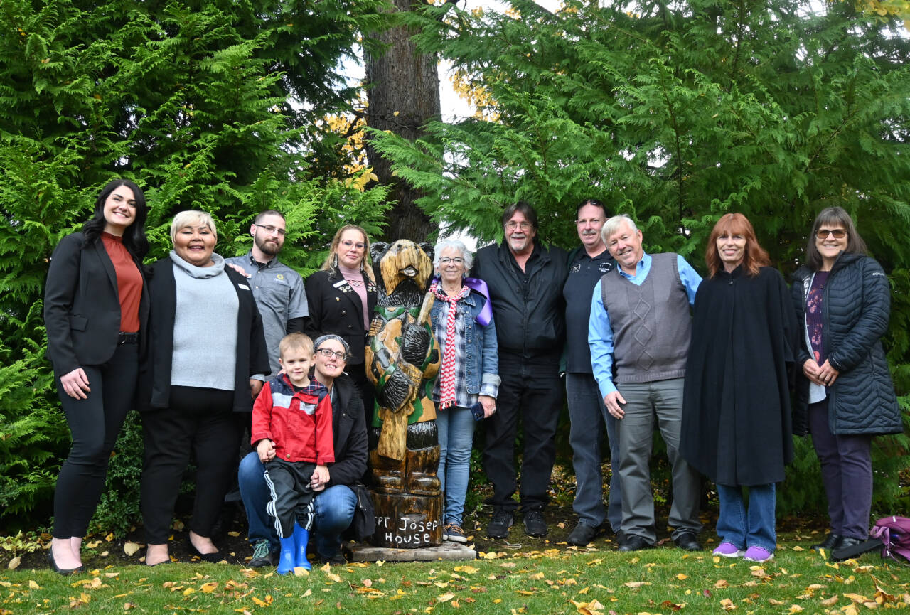 Sequim Gazette photos by Michael Dashiell
Representatives from Black Bear Diner and Sequim Holiday Inn Suites present Betsy Reed Schultz (center), founder of Captain Joseph House, with a carved bear to enhance the outdoor area at the Port Angeles respite facility. The donation also came with a $2,500 donation from Black Bear Diners corporate office. Pictured are, from left: Namaste Stayton, vice president of hotel operations with Wirta Hospitality Worldwide; Yolanda Pompa, Quality Inn Suites general manager; Jerry Spars, maintenance staffer at Quality Inn Suites; Amanda Gerhard, Quality Inn Suites guest relations; Schultz; Kevin Merrigan, Holiday Inn Express Suites maintenance manager; Eric Hicks, Black Bear Diner assistant manager; Bret Wirta, owner of Wirta Hospitality Worldwide; Nancy Merrigan, Quality Inn Suites general manager; Claire Rausch, volunteer at Captain Joseph House; and (in front) Nicole Merrigan and son Isiah.