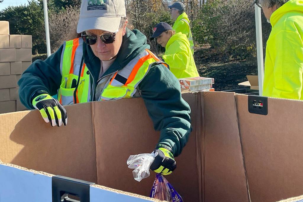 Sequim Gazette photo by Matthew Nash/ Laura Johns, a Community Emergency Member Team (CERT) member, readies some food for the Family Holiday Meal Bag Distribution program.