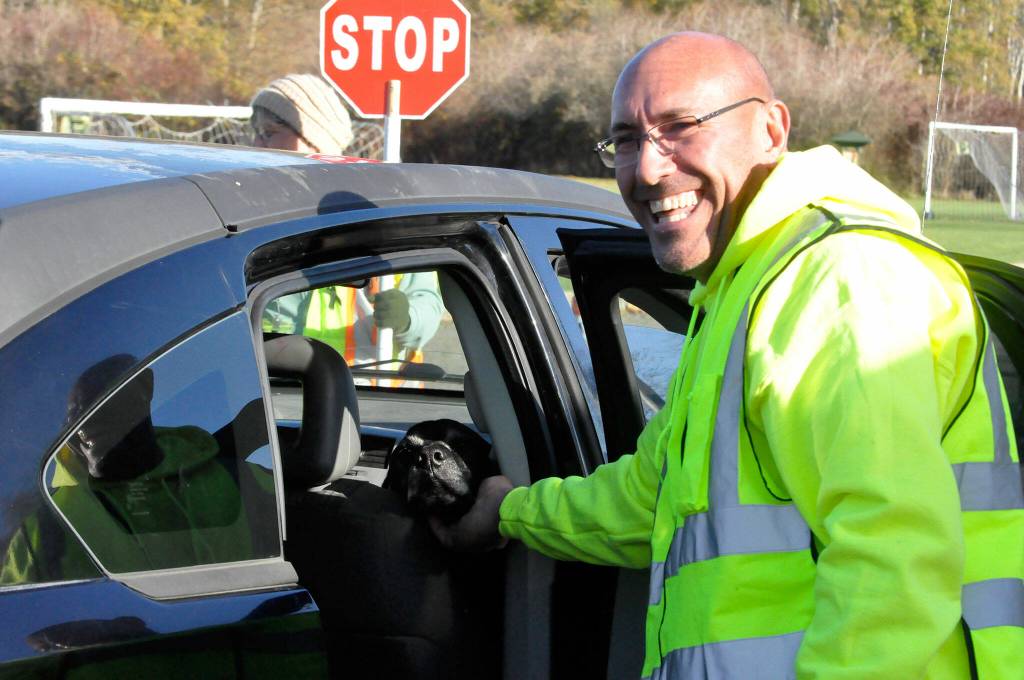 Sequim Gazette photo by Matthew Nash/ Volunteer Lynie Staus greets a dog during the Family Holiday Meal Bag Distribution program that helped provide more than 1,000 meal boxes on Nov. 17.