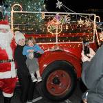 Sequim Gazette file photo by Matthew Nash/ Veronica Weatherly holds her son Tucker for a photo-op with Santa Claus in 2021 as her husband Doug takes a photo. Santas Toy and Food Fire Brigade tours Sequim again Dec. 4-7.