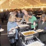 Photo by Keith Thorpe/Olympic Peninsula News Group / Guests at the Dec. 8 gala benefiting the Joe Rantz Rotary Youth Fund go through a food serving line under an events tent at the Sequim Museum & Arts following a special showing of the film The Boys in the Boat in Port Angeles.