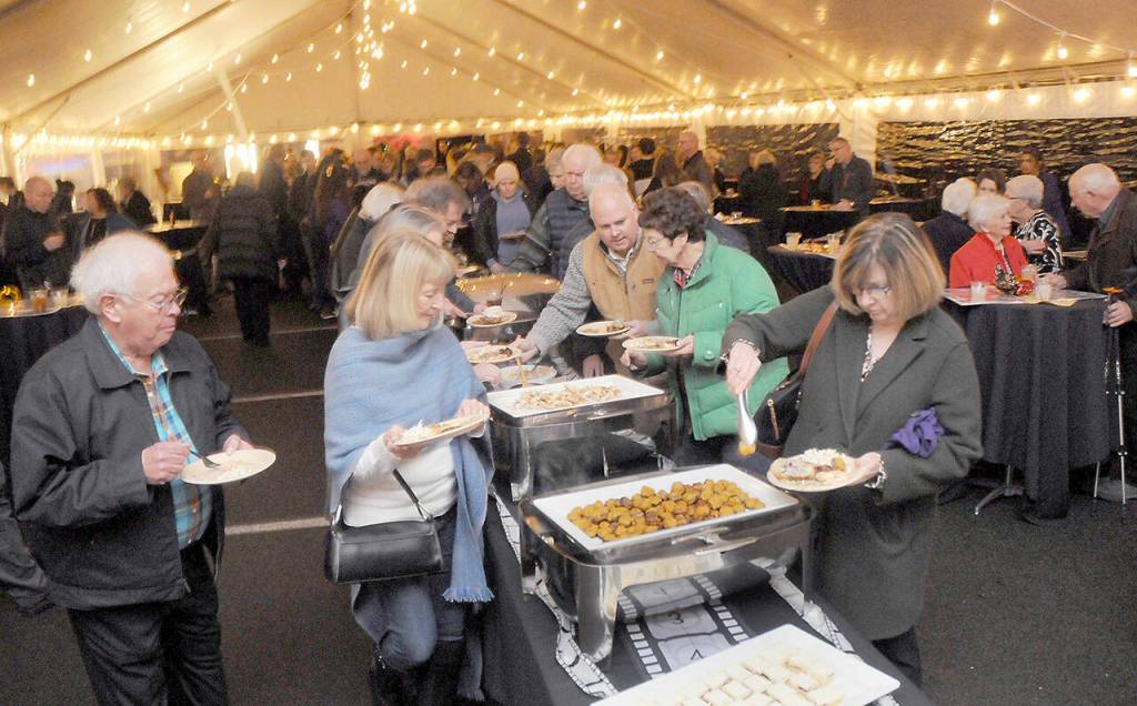 Photo by Keith Thorpe/Olympic Peninsula News Group / Guests at the Dec. 8 gala benefiting the Joe Rantz Rotary Youth Fund go through a food serving line under an events tent at the Sequim Museum & Arts following a special showing of the film The Boys in the Boat in Port Angeles.