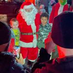 Sequim Gazette photo by Matthew Nash/ Damian Frederick, 6, and Dominic Cooper, 9, take some photos for family with Santa Claus during Santas Toy and Food Brigades tour across Sequim on Dec. 6.