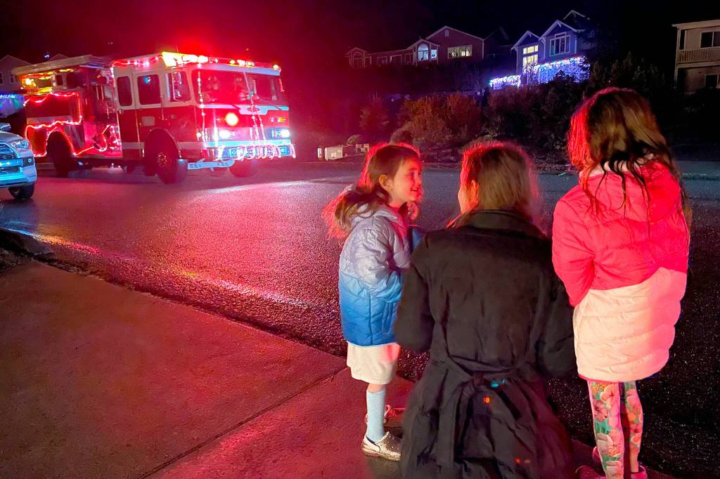Sequim Gazette photo by Matthew Nash/ Emily Klatt and her daughters Elle and Eden Kazerouninia see Santa coming down their street on Dec. 6 with Santas Toy and Food Brigade.