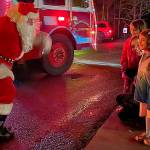 Sequim Gazette photo by Matthew Nash/ Santa Claus greets Emily Klatt and her daughters Elle and Eden Kazerouninia during Santas Toy and Food Brigades tour across Sequim on Dec. 6.