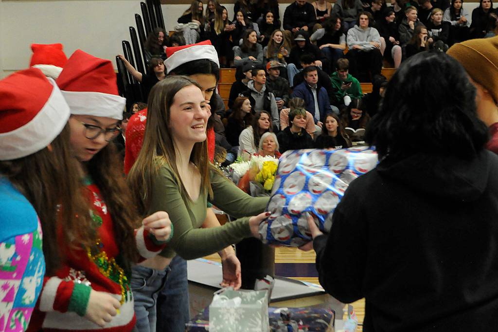Sequim Gazette photo by Matthew Nash
Ellie Woodford with Sequim High Schools Leadership class hands out a present during the schools annual Winter Wishes assembly on Dec. 18. See story, more photos on A-3.