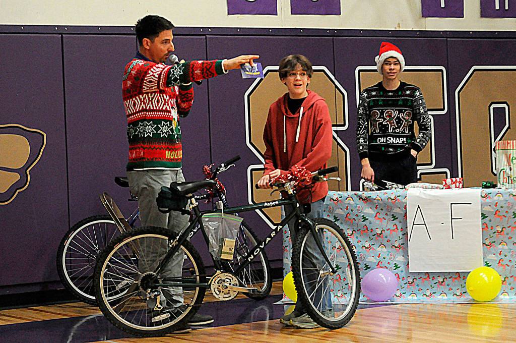 Sequim Gazette photo by Matthew Nash/ Teacher Sean OMera encourages Nathan Mavy to try out his new bicycle he received at the Winter Wishes assembly.