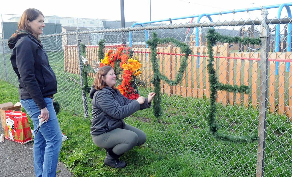 Photo by Keith Thorpe/Olympic Peninsula News Group / Jo Johnston, left, and Leia Kenton spell out a message of hope on the fence of Erickson Playfield after the Dream Playground was burned on Dec. 20 in Port Angeles.