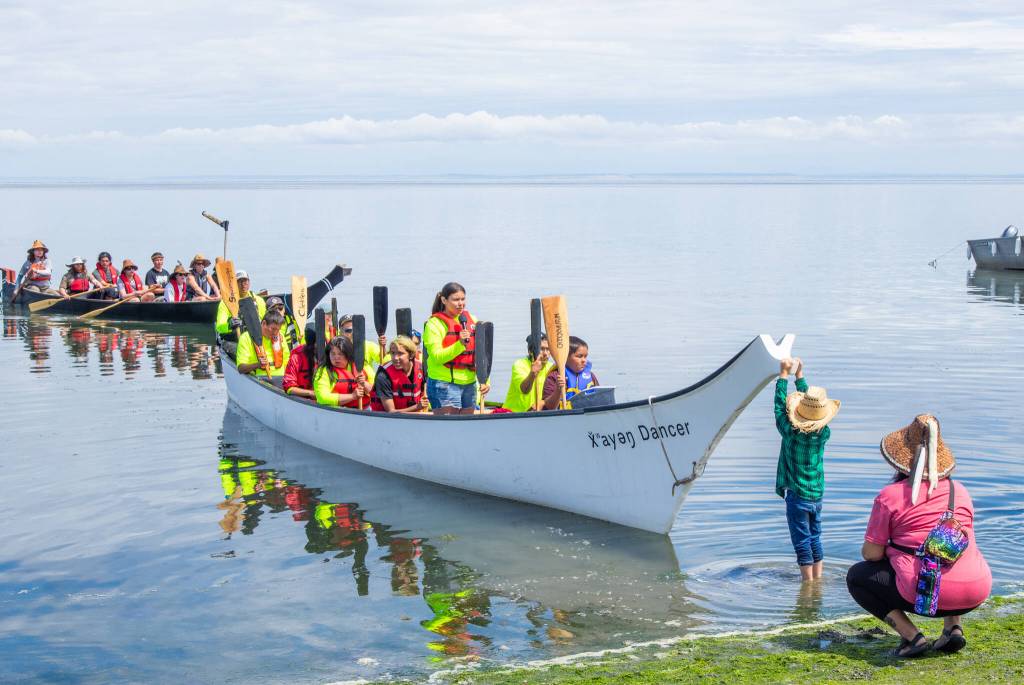 Sequim Gazette photo by Emily Matthiessen
Josiah Powless, 7-years-old, holds the bow of a canoe as a member of the canoe family requests permission to land on Jamestown SKlallam Tribes shoreline in July.