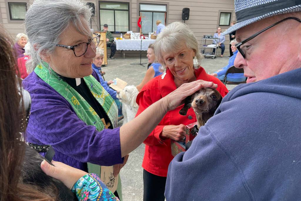 Sequim Gazette photo by Matthew Nash
Pastor Desi Larson blesses Abby the dog as owner Joel Swenning and church member JoAnn Sahs-Cavin, in middle, look on during a Blessing of the Animals ceremony on Oct. 8 at Trinity United Methodist Church.