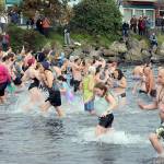 Participants in the New Year's Day polar bear dip in Port Angeles run in and out of the chilly water of Port Angeles Harbor at Hollywood Beach as onlookers watch from the shore on Monday. More than 100 dippers took part in the annual ritual, which served as a fundraiser for Volunteer Hospice of Clallam County. (Keith Thorpe/Peninsula Daily News)