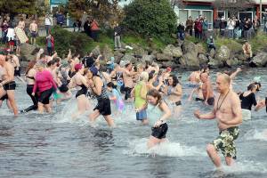 Participants in the New Year's Day polar bear dip in Port Angeles run in and out of the chilly water of Port Angeles Harbor at Hollywood Beach as onlookers watch from the shore on Monday. More than 100 dippers took part in the annual ritual, which served as a fundraiser for Volunteer Hospice of Clallam County. (Keith Thorpe/Peninsula Daily News)
