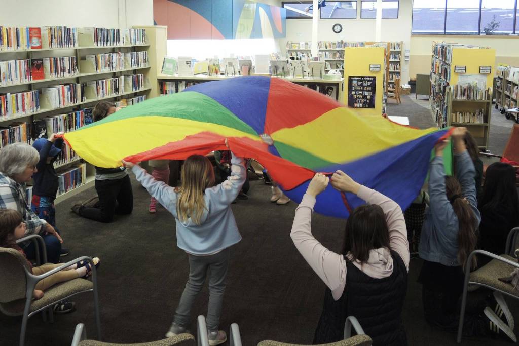 Photo courtesy of North Olympic Library System
Families play with a brightly colored parachute on Jan. 2 at Storytime in the Sequim Library.